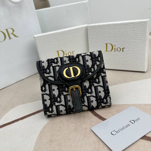这款 Dior Bobby 银包是 2023 年夏季的最新款式 设计小巧而实用 以蓝色 Dior Oblique 缇花制成 采用两折设计 正面翻盖缀以 Cd 扣